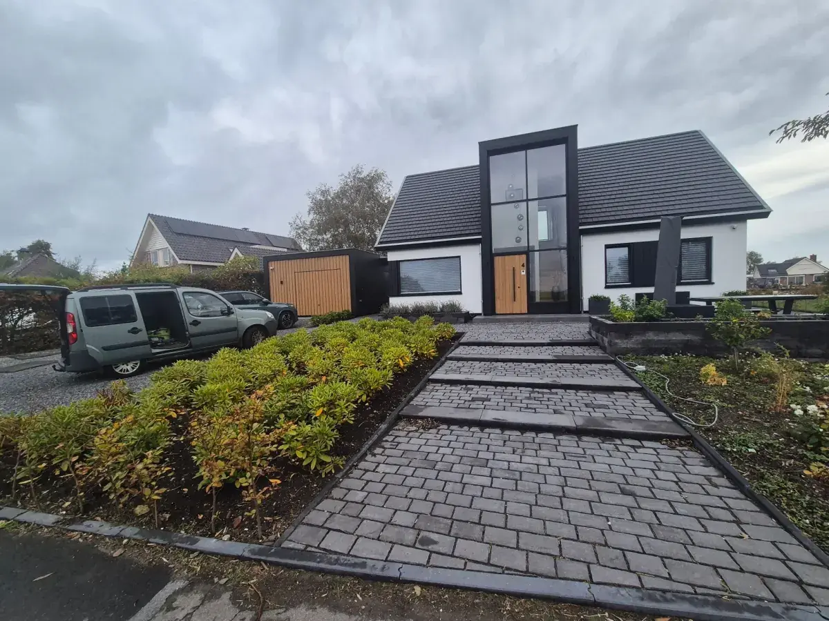 Aangelegde voortuin met brede bestrating en groene plantvakken